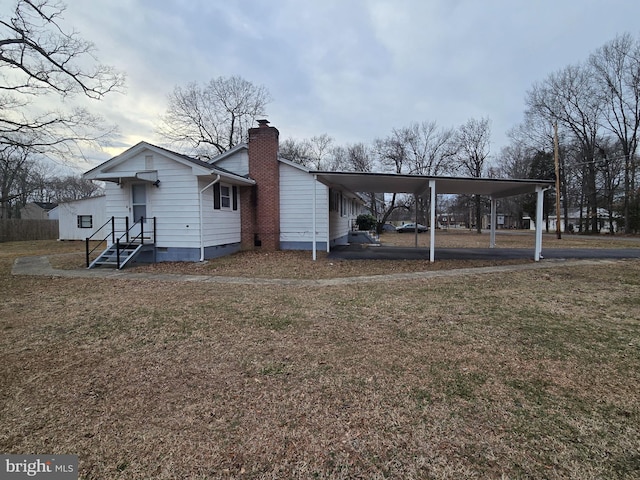 back of house with crawl space, a chimney, a lawn, and a carport