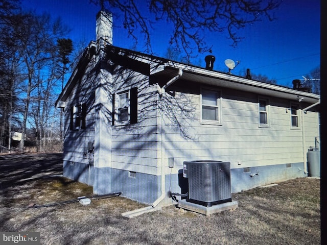 view of property exterior with crawl space, a chimney, and central AC unit