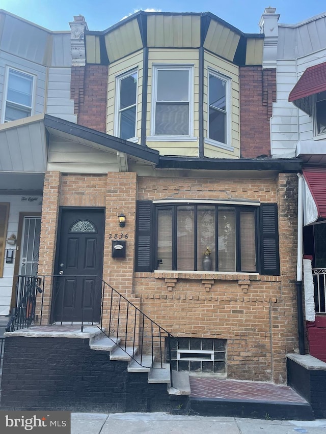 view of exterior entry featuring a chimney and brick siding