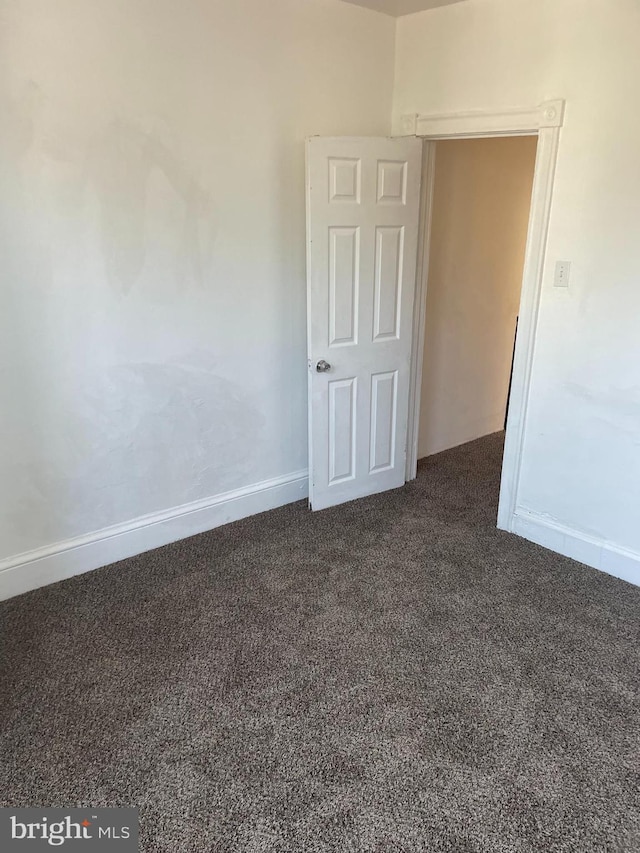 empty room with dark carpet and baseboards