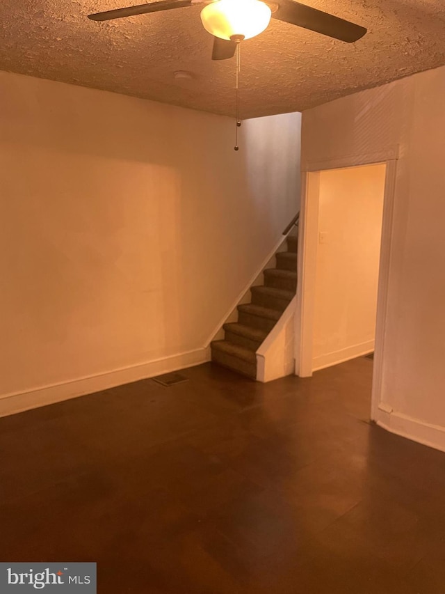 basement with ceiling fan, stairs, baseboards, and a textured ceiling