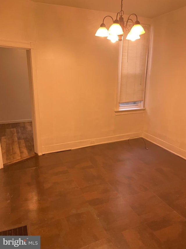 spare room with visible vents, baseboards, and a notable chandelier