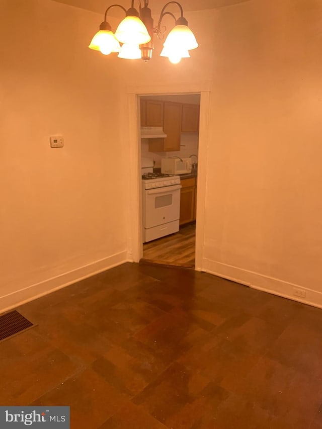 unfurnished dining area with visible vents, a notable chandelier, and baseboards