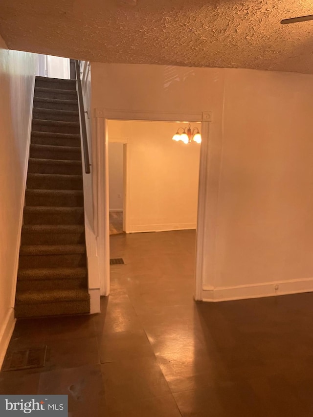 below grade area featuring baseboards, visible vents, stairway, and a textured ceiling