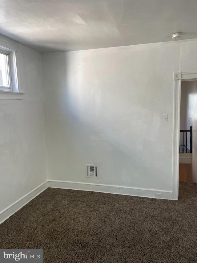 unfurnished room with carpet floors, visible vents, and baseboards