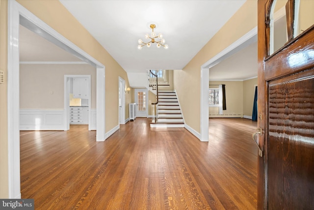 foyer featuring crown molding, wood-type flooring, a chandelier, and baseboard heating