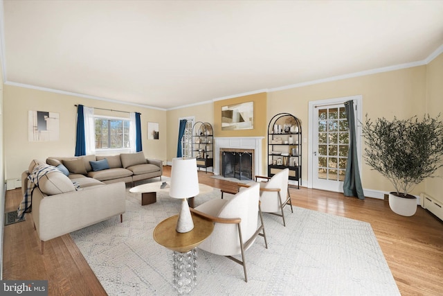 living room with crown molding, baseboard heating, and light wood-type flooring