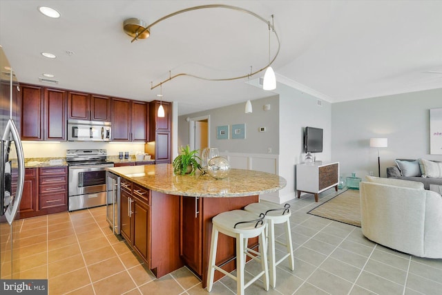 kitchen with light tile patterned floors, stainless steel appliances, hanging light fixtures, and light stone counters