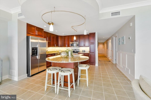 kitchen with decorative light fixtures, light tile patterned floors, stainless steel appliances, and light stone counters