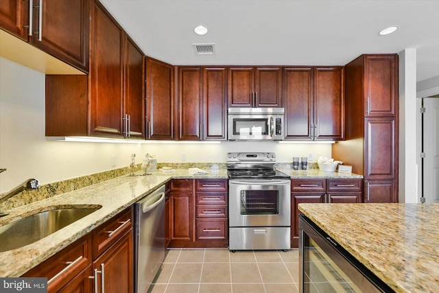 kitchen featuring wine cooler, sink, light stone counters, light tile patterned floors, and appliances with stainless steel finishes