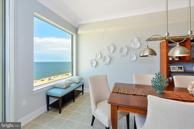 dining room featuring a water view, light tile patterned floors, and a view of the beach