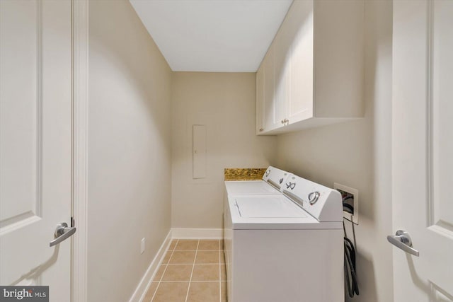 clothes washing area featuring cabinets, washing machine and dryer, and light tile patterned floors