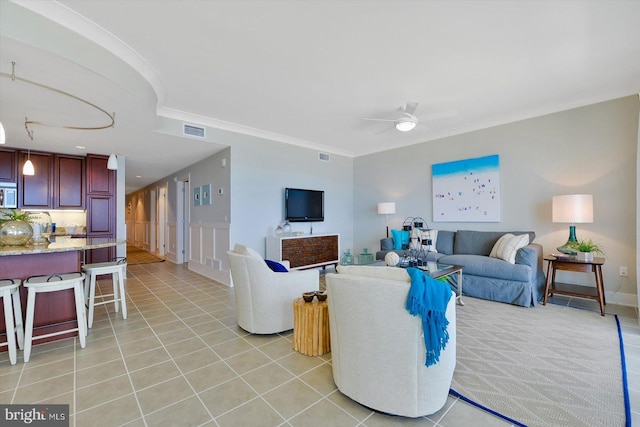 living room with light tile patterned floors, ceiling fan, and ornamental molding