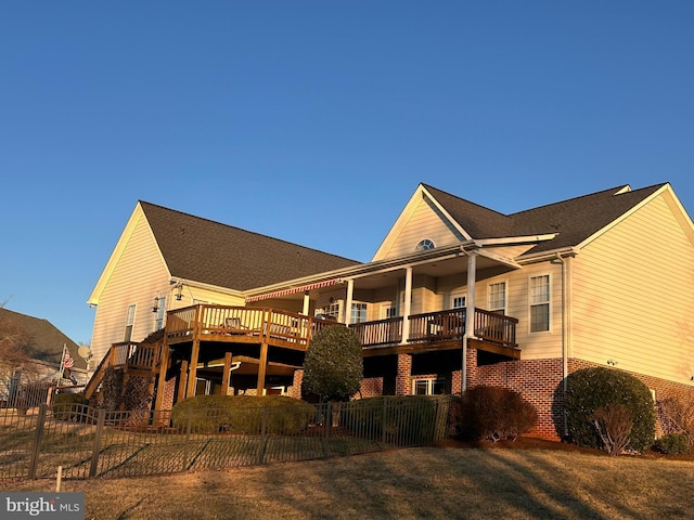 back of house featuring a wooden deck, a balcony, and a yard