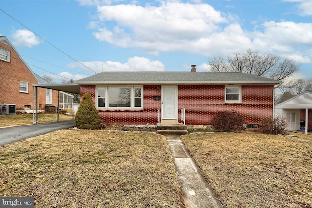 view of front of property featuring brick siding, a front yard, an attached carport, and aphalt driveway