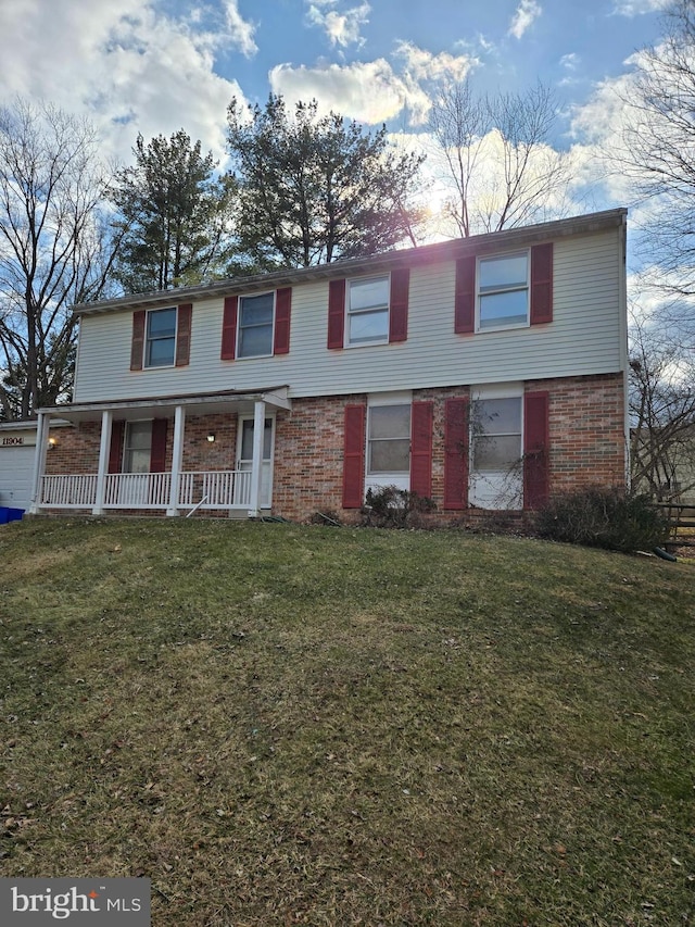 view of front of house with a porch, a front yard, and brick siding