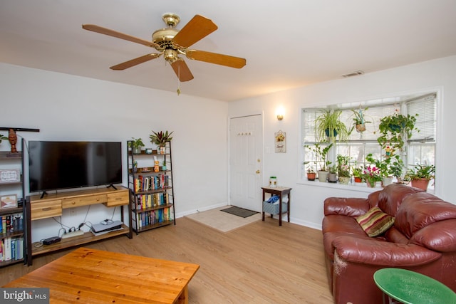 living room with light wood-style floors, visible vents, ceiling fan, and baseboards