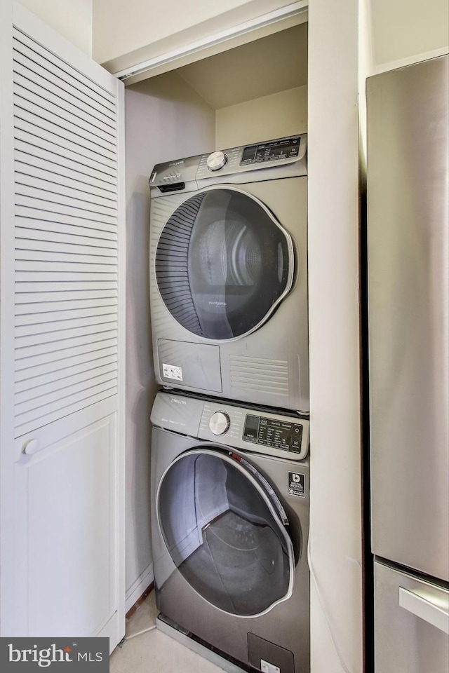 clothes washing area featuring stacked washer and dryer and laundry area