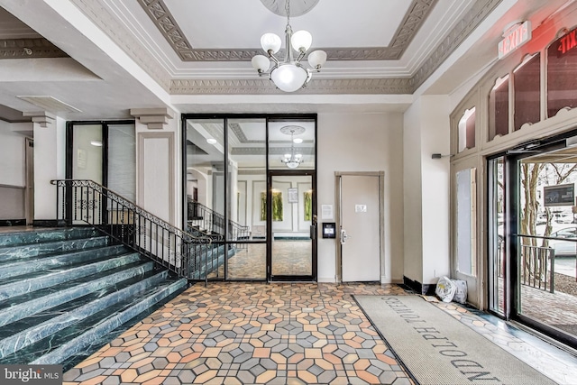 entrance foyer featuring a chandelier, ornamental molding, and stairs