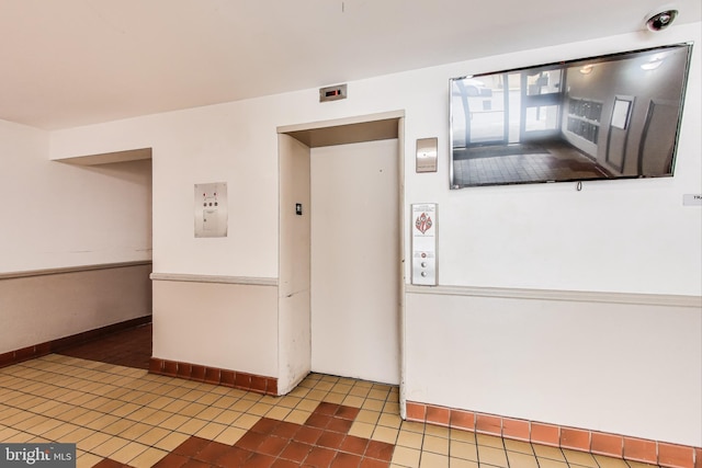 hallway with elevator and tile patterned floors