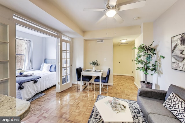 living area featuring a ceiling fan, visible vents, and baseboards