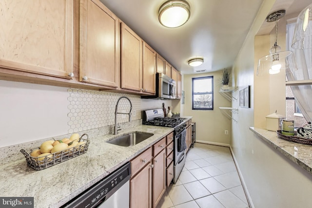 kitchen with appliances with stainless steel finishes, backsplash, a sink, and light stone countertops