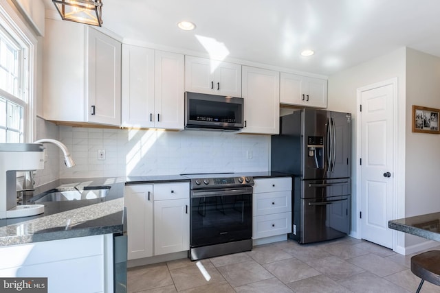 kitchen with appliances with stainless steel finishes, backsplash, a sink, and white cabinets