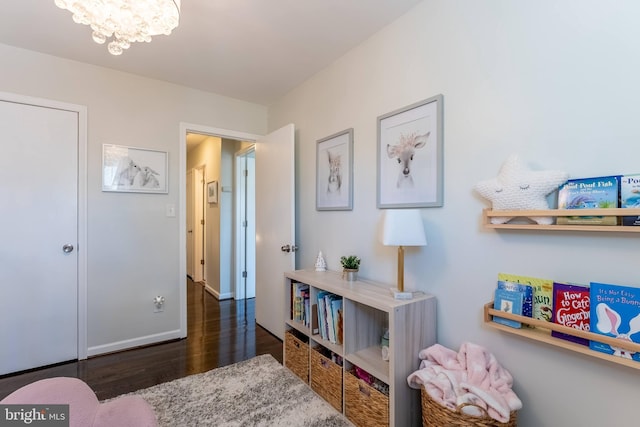 interior space featuring dark wood-type flooring, a notable chandelier, and baseboards