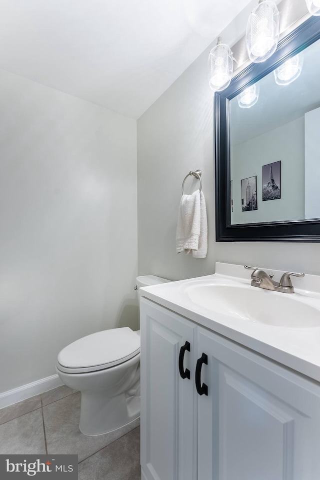 half bathroom with baseboards, vanity, toilet, and tile patterned floors