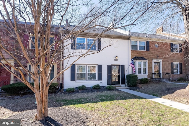 view of property with a front yard, a chimney, and brick siding