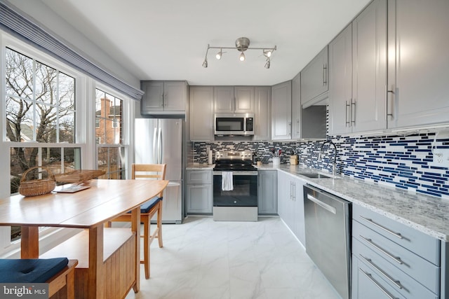 kitchen featuring marble finish floor, stainless steel appliances, gray cabinetry, and a sink