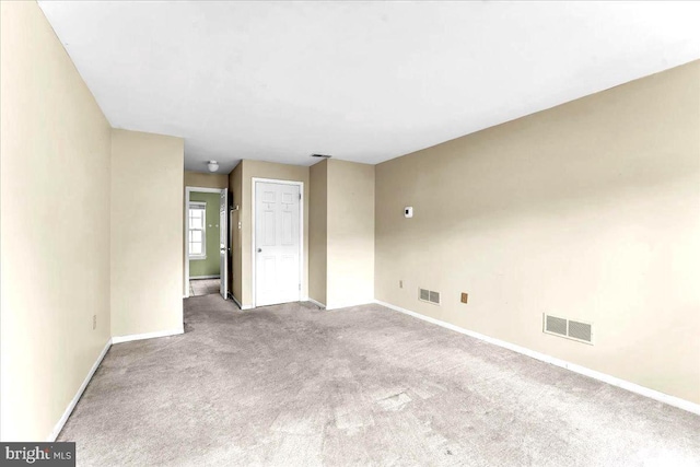 unfurnished room with baseboards, visible vents, and light colored carpet