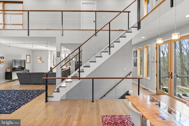 stairway with baseboards, recessed lighting, french doors, a towering ceiling, and wood finished floors