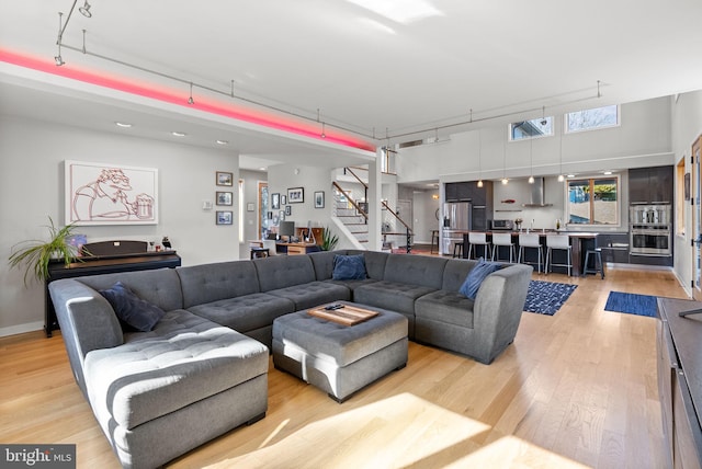 living area featuring stairway, a high ceiling, and light wood finished floors