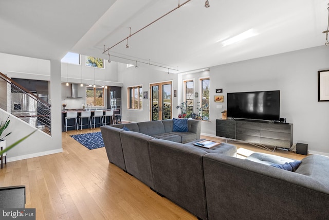 living room featuring a high ceiling, rail lighting, baseboards, and wood-type flooring