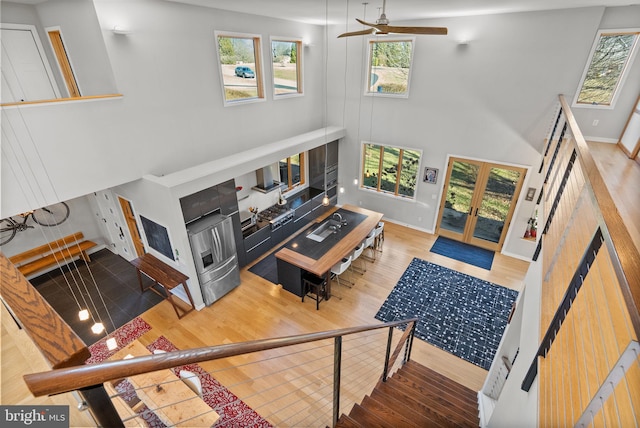 living area with a glass covered fireplace, plenty of natural light, wood finished floors, and a ceiling fan