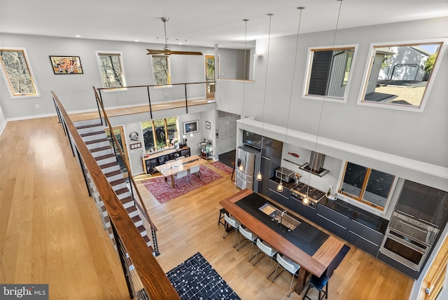 living room with a high ceiling, recessed lighting, wood finished floors, and baseboards