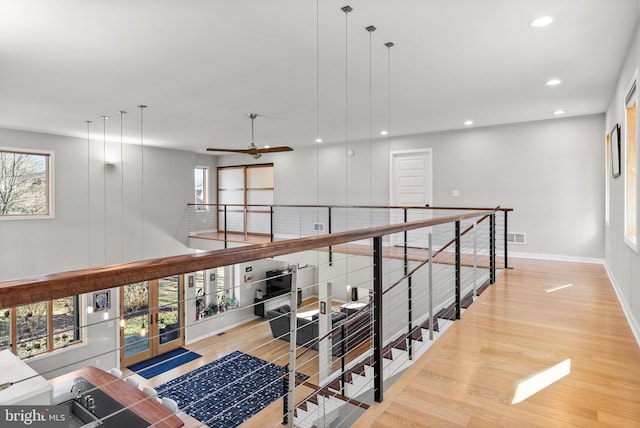 hall featuring visible vents, an upstairs landing, wood finished floors, recessed lighting, and baseboards