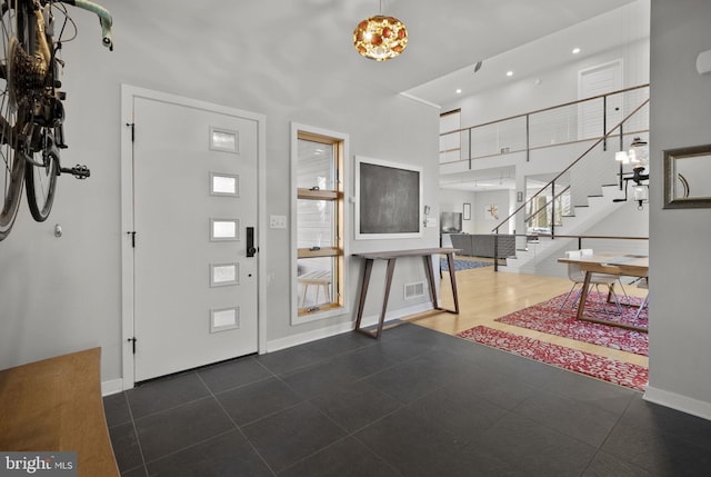 entryway featuring visible vents, stairway, a high ceiling, an inviting chandelier, and baseboards