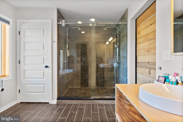 full bathroom with vanity, baseboards, a stall shower, and wood finish floors