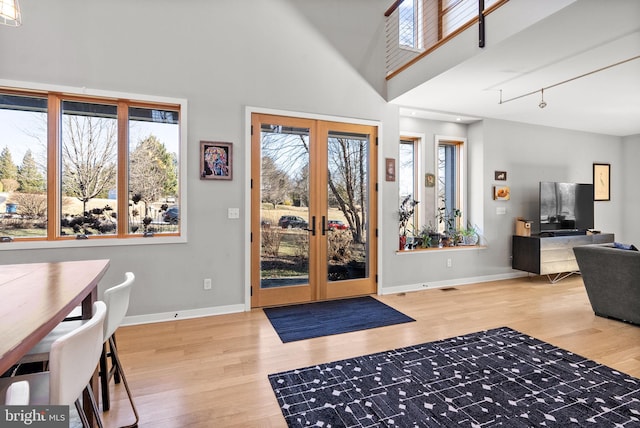 foyer entrance featuring visible vents, wood finished floors, french doors, baseboards, and a towering ceiling