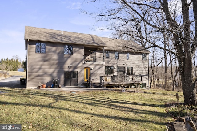 back of property with a yard, a wooden deck, and a balcony