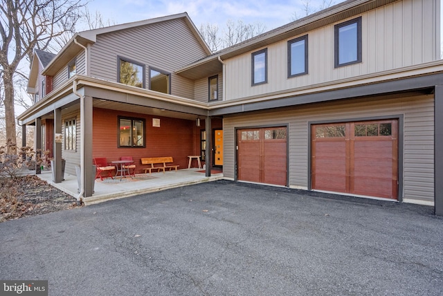 view of front of home with a patio area, an attached garage, and driveway