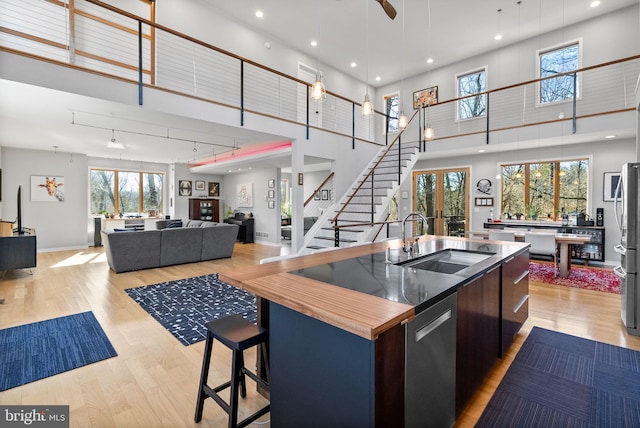 kitchen with a kitchen island with sink, stainless steel appliances, a sink, light wood-style floors, and modern cabinets