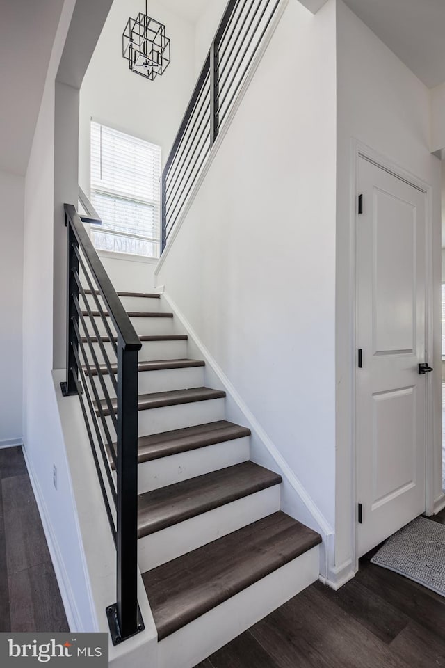 stairs featuring baseboards, a notable chandelier, and wood finished floors