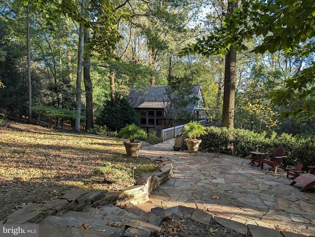 rear view of property featuring a shingled roof and a patio