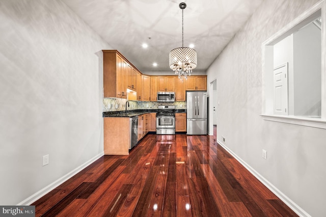 kitchen with sink, appliances with stainless steel finishes, decorative backsplash, dark hardwood / wood-style flooring, and decorative light fixtures