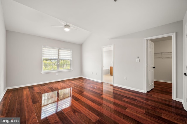 unfurnished bedroom with lofted ceiling, a walk in closet, dark hardwood / wood-style floors, a closet, and ceiling fan