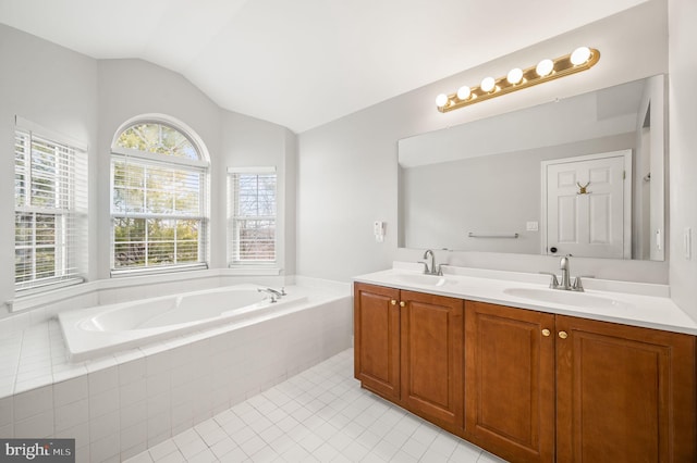 bathroom featuring lofted ceiling, tiled tub, vanity, and plenty of natural light