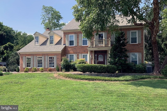 view of front facade featuring roof with shingles, brick siding, and a front lawn